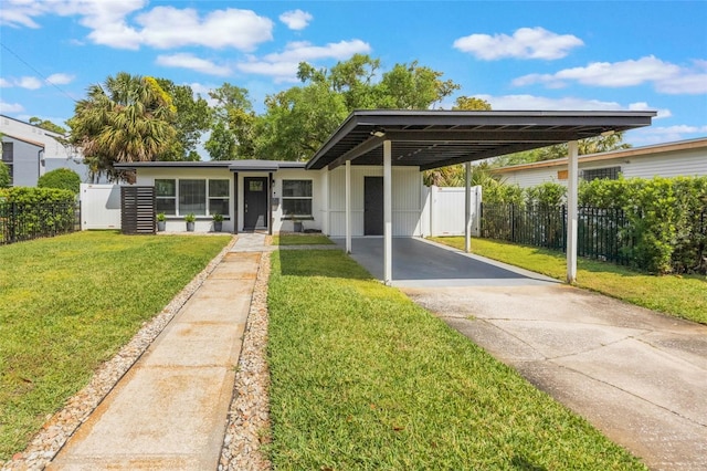 view of front facade with a front yard, concrete driveway, a carport, and fence
