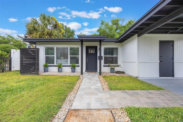 view of exterior entry with a lawn and fence