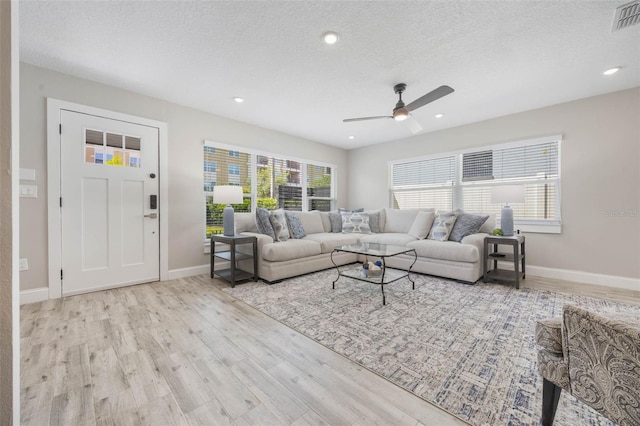 living room with a ceiling fan, visible vents, a textured ceiling, and wood finished floors