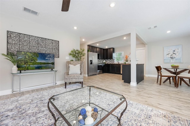 living room featuring light wood finished floors, visible vents, and recessed lighting