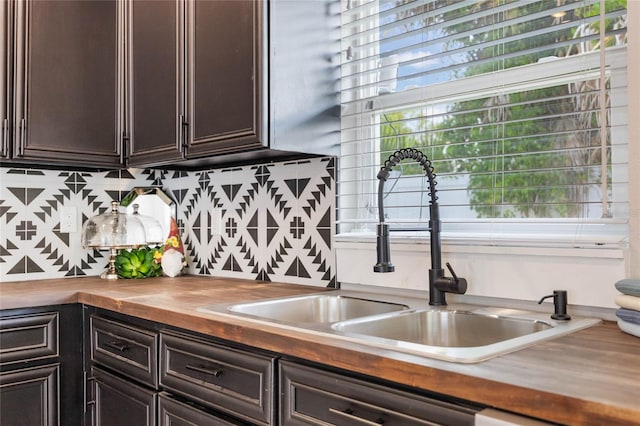 kitchen featuring a sink, dark brown cabinetry, a wealth of natural light, and butcher block counters