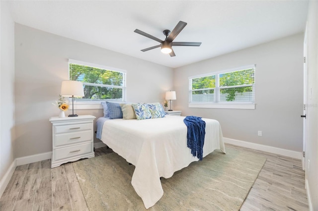 bedroom with light wood finished floors, multiple windows, and baseboards