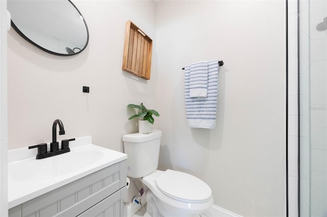 bathroom featuring toilet, vanity, baseboards, and tiled shower