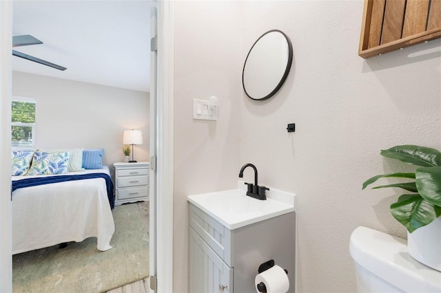 ensuite bathroom with ensuite bath, ceiling fan, toilet, and vanity
