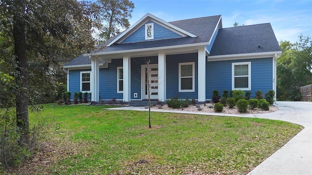 view of front of home with covered porch, a front yard, concrete driveway, and roof with shingles