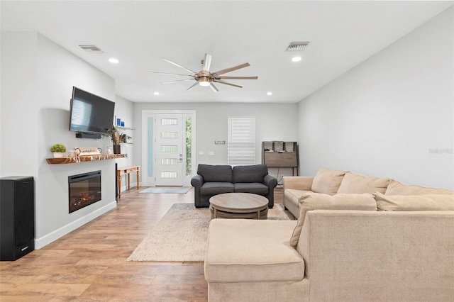 living area with visible vents, light wood finished floors, recessed lighting, a ceiling fan, and a glass covered fireplace