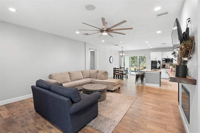 living area featuring light wood-style flooring, recessed lighting, ceiling fan, and visible vents