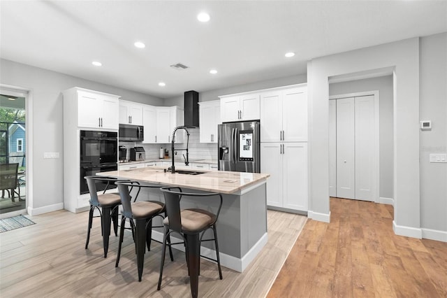 kitchen featuring visible vents, light stone countertops, stainless steel appliances, a sink, and an island with sink