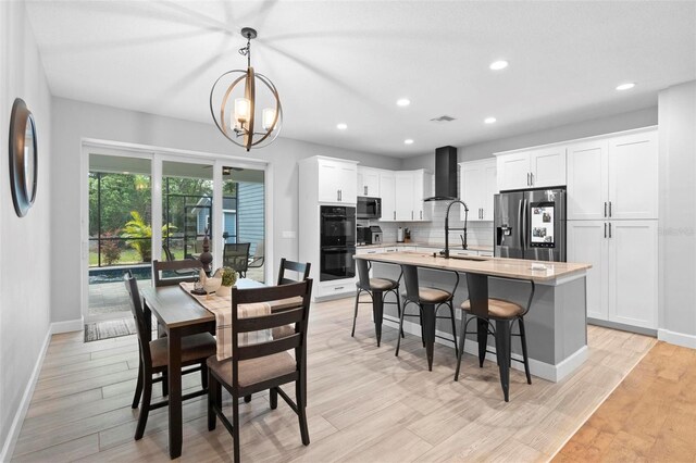 dining room featuring a notable chandelier, baseboards, light wood-style floors, and visible vents