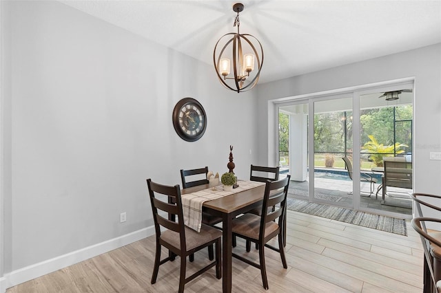 dining area with light wood-style flooring, baseboards, and a chandelier