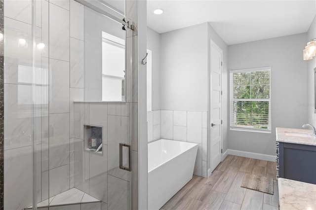 bathroom featuring vanity, a freestanding tub, baseboards, a shower stall, and wood finished floors