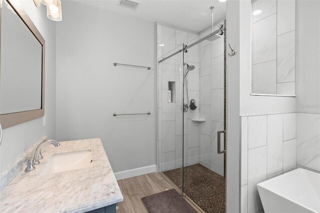bathroom featuring a stall shower, visible vents, wood finished floors, and a freestanding tub