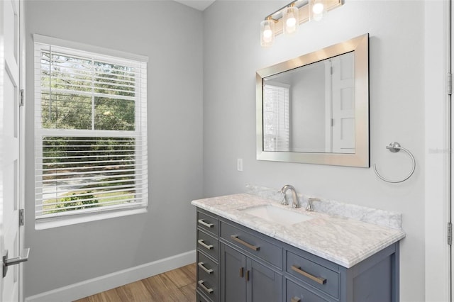 bathroom with plenty of natural light, baseboards, wood finished floors, and vanity