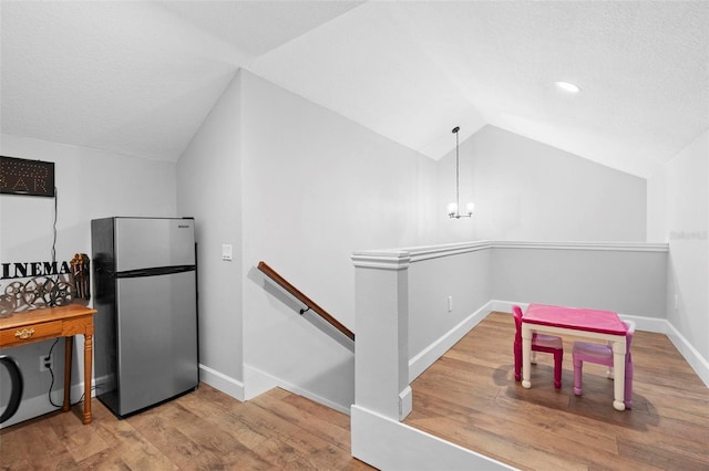 kitchen featuring freestanding refrigerator, baseboards, lofted ceiling, and wood finished floors
