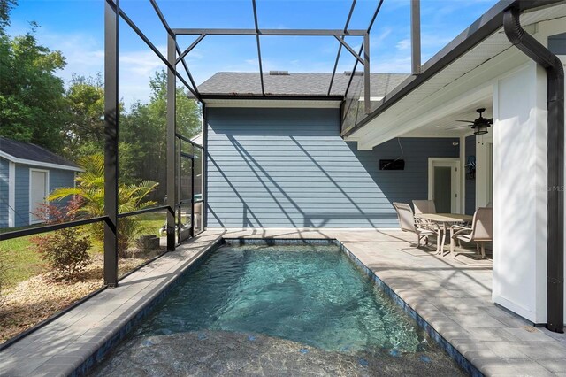outdoor pool featuring glass enclosure, a patio area, and ceiling fan