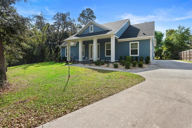 view of front of home featuring concrete driveway, fence, a front yard, covered porch, and a shingled roof