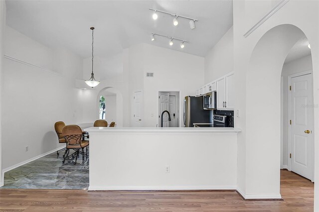 7606 Fordham Creek Ln, Orlando, FL 32818 - kitchen with arched walkways, range, stainless steel microwave, white cabinets, and a peninsula