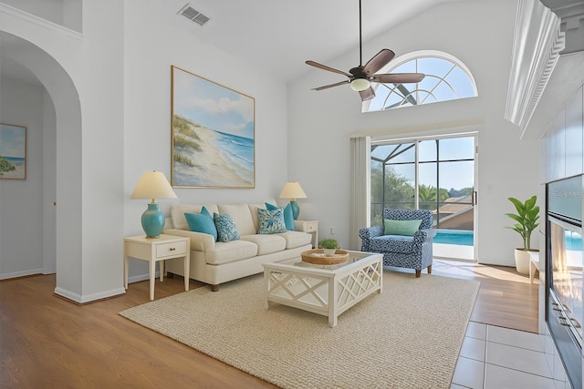 7606 Fordham Creek Ln, Orlando, FL 32818 - living area featuring ceiling fan, arched walkways, high vaulted ceiling, a sunroom, and wood finished floors