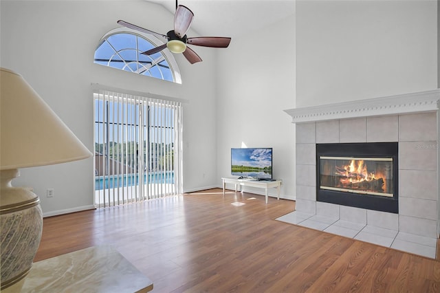 7606 Fordham Creek Ln, Orlando, FL 32818 - living area featuring wood finished floors, a tile fireplace, a ceiling fan, and a towering ceiling