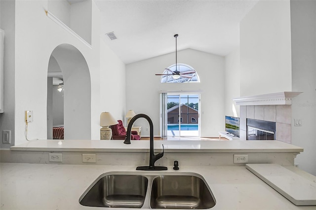 7606 Fordham Creek Ln, Orlando, FL 32818 - kitchen featuring ceiling fan, a tile fireplace, pendant lighting, arched walkways, and light countertops