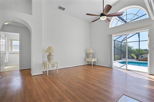 7606 Fordham Creek Ln, Orlando, FL 32818 - unfurnished room featuring high vaulted ceiling, healthy amount of natural light, arched walkways, ceiling fan, and wood finished floors