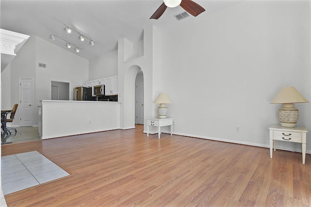 7606 Fordham Creek Ln, Orlando, FL 32818 - unfurnished living room featuring high vaulted ceiling, a ceiling fan, arched walkways, and light wood-style flooring