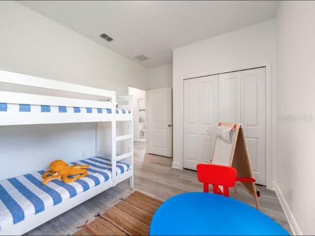 bedroom featuring a closet, visible vents, wood finished floors, and baseboards
