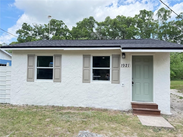 view of front of property with roof with shingles, stucco siding, and entry steps