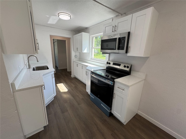 kitchen featuring dark wood-style flooring, baseboards, white cabinetry, stainless steel appliances, and a sink