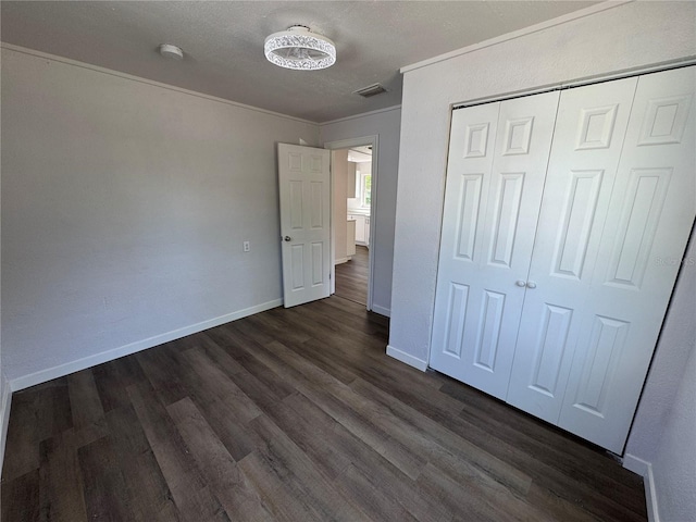 unfurnished bedroom featuring a closet, visible vents, baseboards, and dark wood-style floors