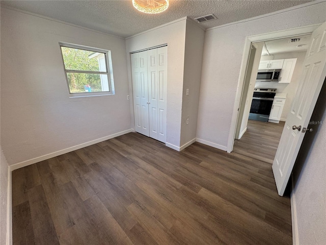 unfurnished bedroom with dark wood finished floors, a textured ceiling, a closet, visible vents, and baseboards