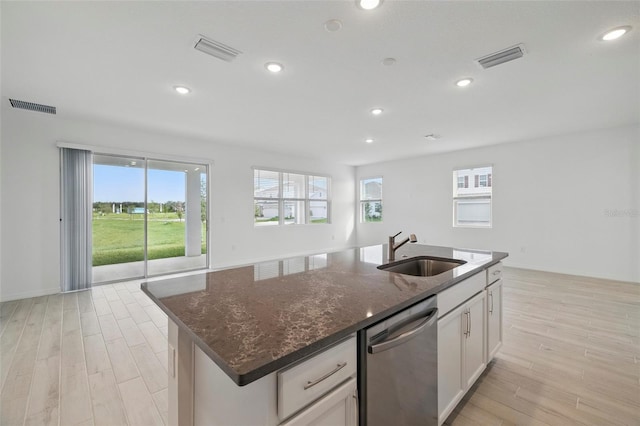 2152 Rock Maple Bnd, Kissimmee, FL 34746 - kitchen with dishwasher, a kitchen island with sink, dark stone countertops, light wood-type flooring, and recessed lighting