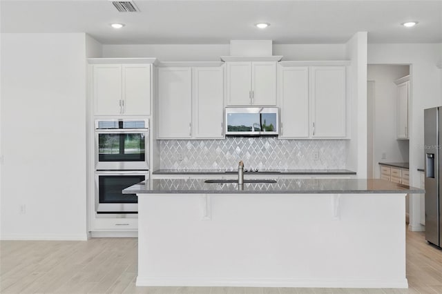 2152 Rock Maple Bnd, Kissimmee, FL 34746 - kitchen featuring stainless steel appliances, light wood finished floors, a kitchen island with sink, backsplash, and recessed lighting