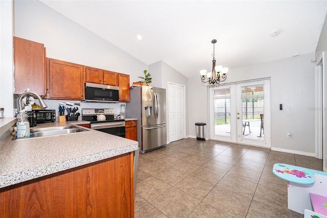 kitchen featuring brown cabinetry, vaulted ceiling, appliances with stainless steel finishes, light countertops, and a notable chandelier