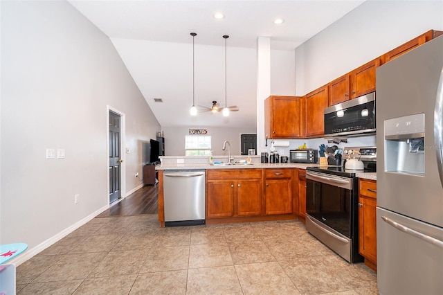 kitchen with a peninsula, light countertops, brown cabinets, appliances with stainless steel finishes, and a sink