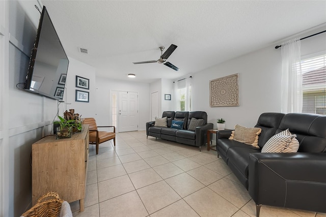 living area with ceiling fan, visible vents, and light tile patterned floors