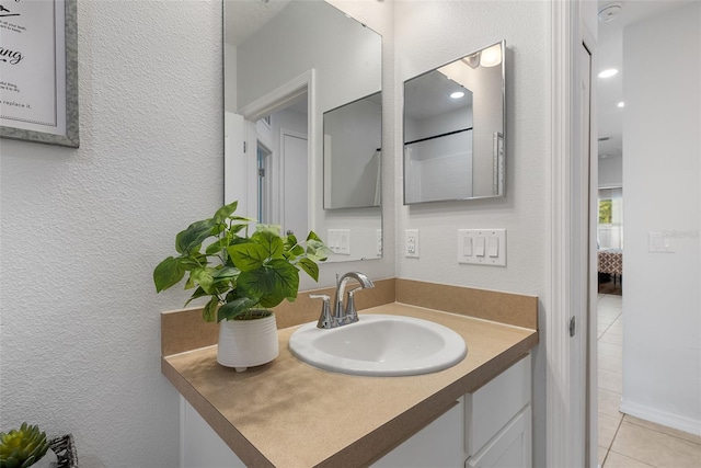 bathroom featuring tile patterned floors, vanity, and a textured wall