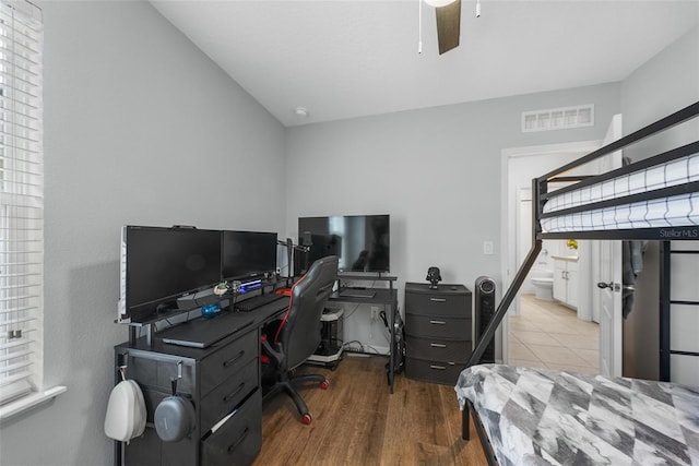 bedroom with visible vents, ensuite bathroom, a ceiling fan, vaulted ceiling, and wood finished floors