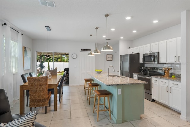 kitchen with visible vents, a sink, a kitchen bar, stainless steel appliances, and decorative backsplash