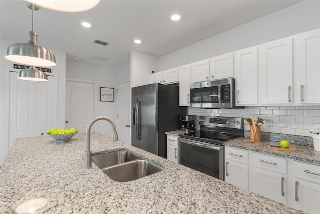 kitchen featuring white cabinets, light stone countertops, stainless steel appliances, a sink, and hanging light fixtures