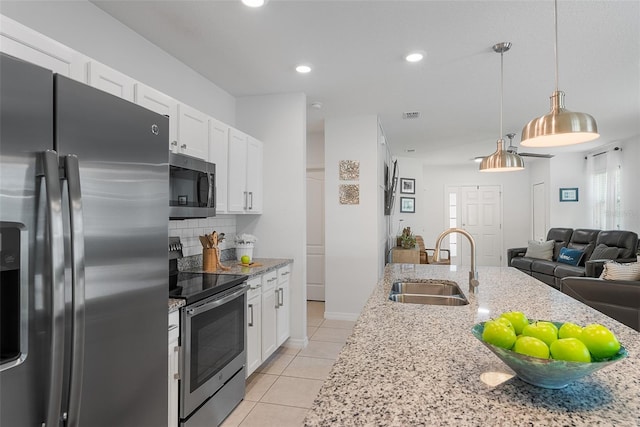 kitchen with open floor plan, white cabinetry, light tile patterned flooring, appliances with stainless steel finishes, and a sink