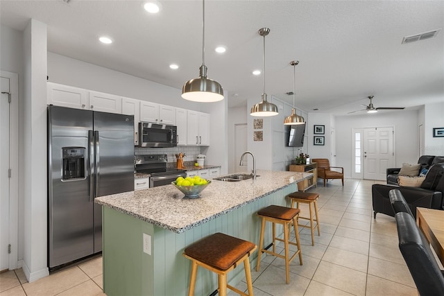 kitchen featuring light tile patterned floors, open floor plan, visible vents, stainless steel appliances, and a sink