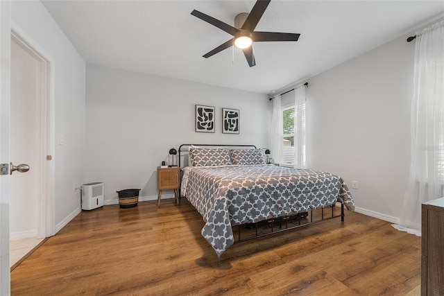 bedroom with wood finished floors, baseboards, and a ceiling fan