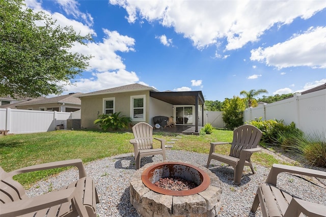 rear view of property featuring a fenced backyard, stucco siding, a lawn, an outdoor fire pit, and a patio