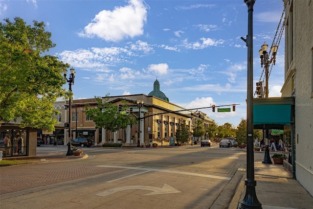 view of road featuring sidewalks, street lights, curbs, and traffic lights