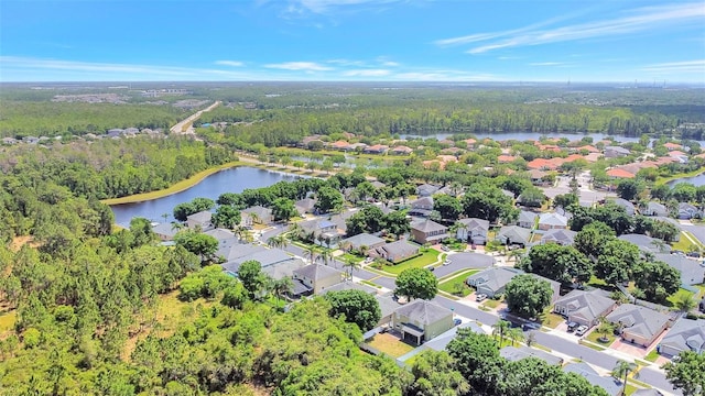 drone / aerial view featuring a residential view, a water view, and a view of trees