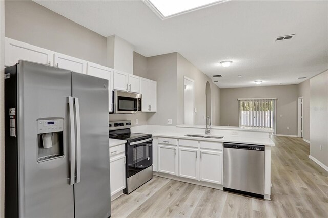 kitchen featuring light countertops, a sink, white cabinets, a peninsula, and appliances with stainless steel finishes
