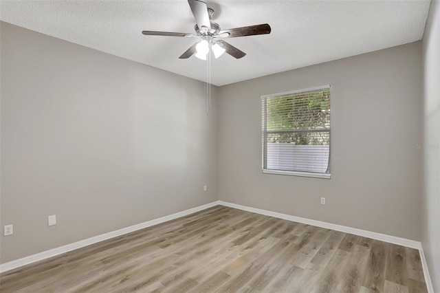 spare room featuring a textured ceiling, baseboards, light wood-style flooring, and a ceiling fan