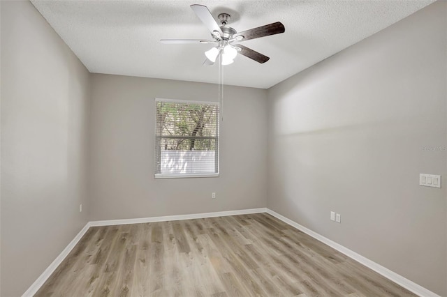 spare room with light wood finished floors, baseboards, ceiling fan, and a textured ceiling