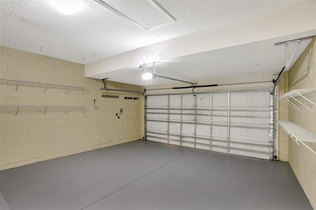 garage with a garage door opener and concrete block wall